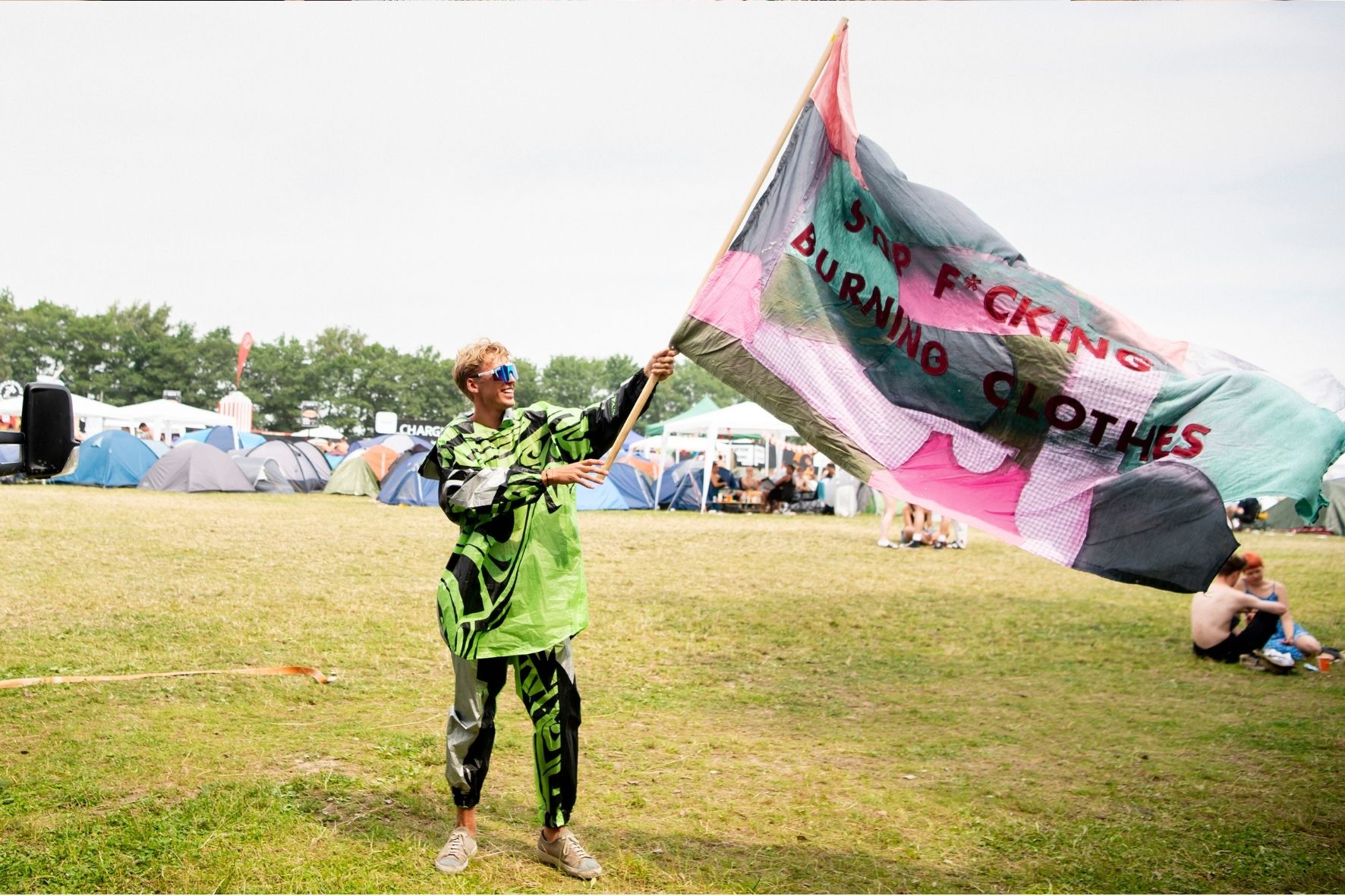Ung mand vifter flag på Roskilde festival med budskab om at man skal stoppe med at brænde tøj